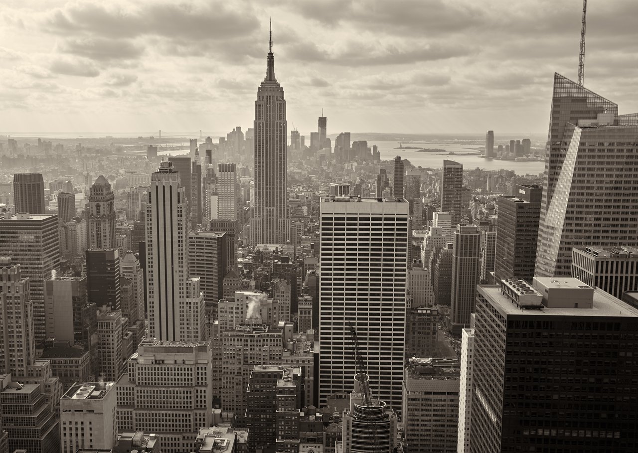 Vista panorámica de rascacielos de Nueva York al atardecer con un enfoque en un apartamento de lujo con balcón iluminado