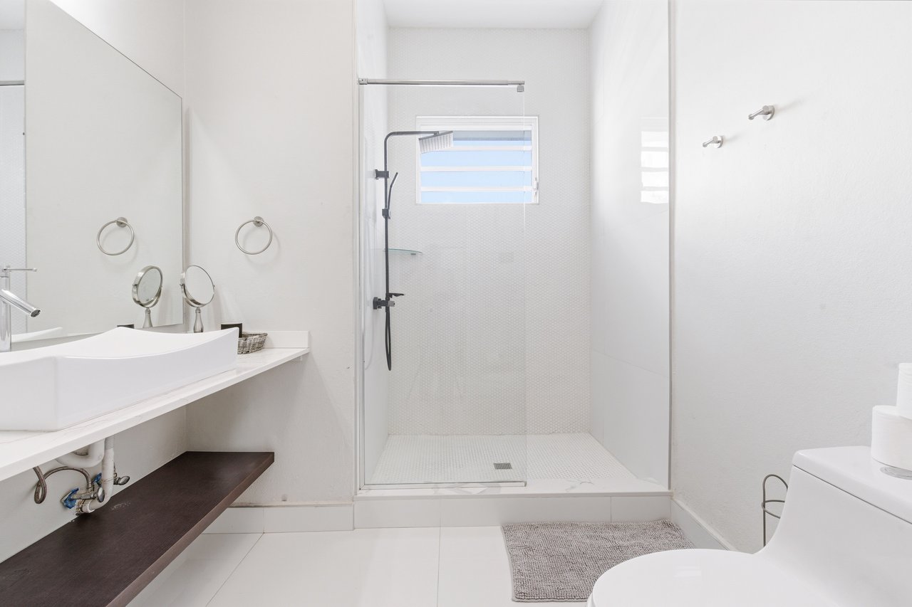 Bright bathroom with a glass walk-in shower, vessel sink, and floating counter.