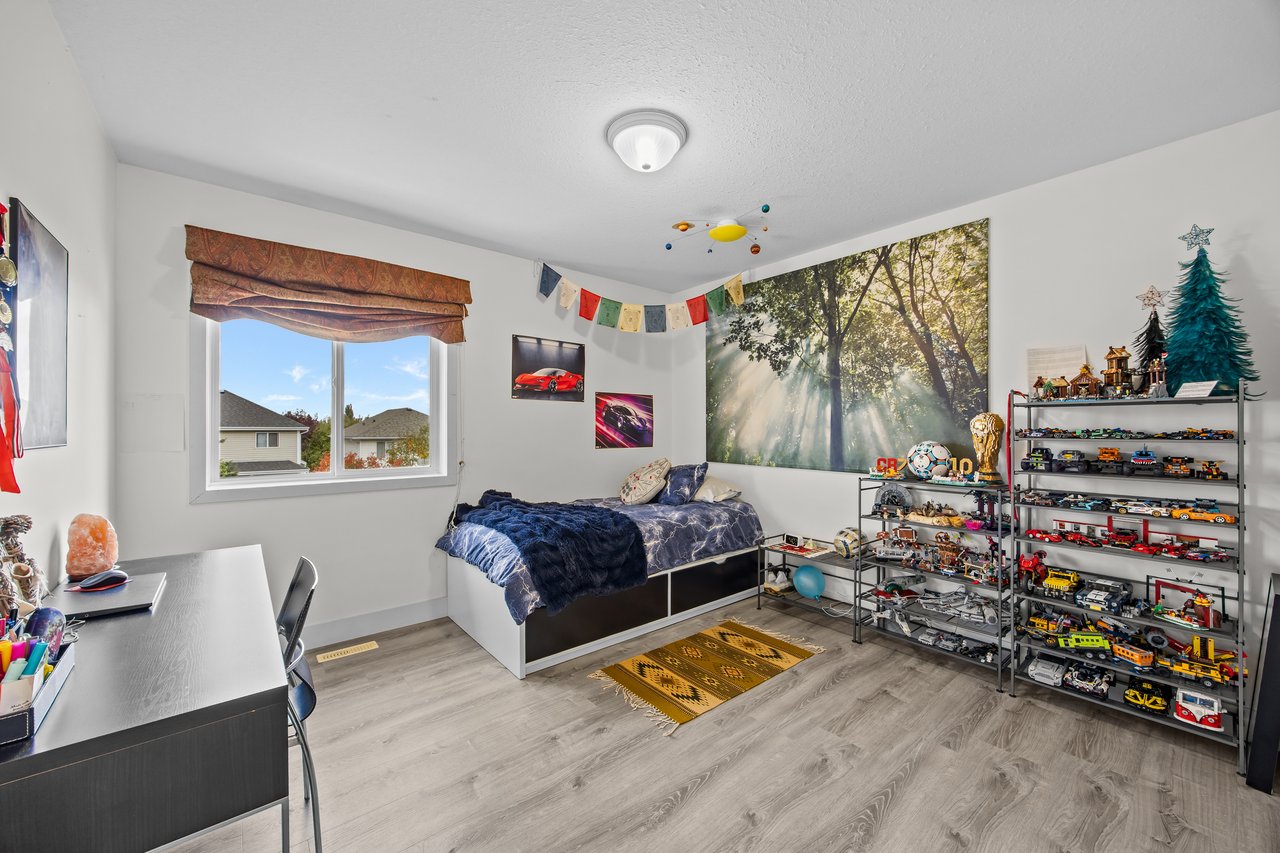 Bedroom with a forest mural, a single bed, and shelves displaying toy cars.