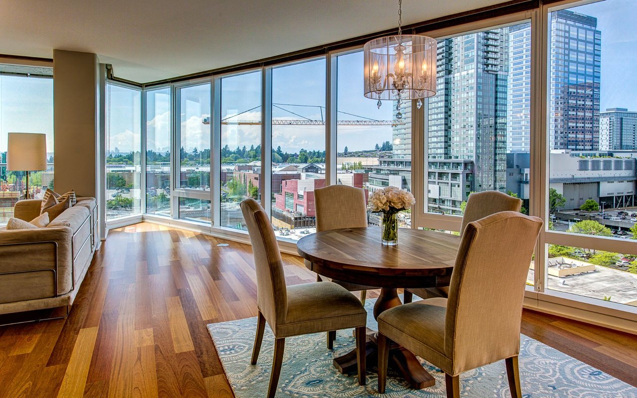 An indoor shot of a modern apartment with floor-to-ceiling windows overlooking a city view