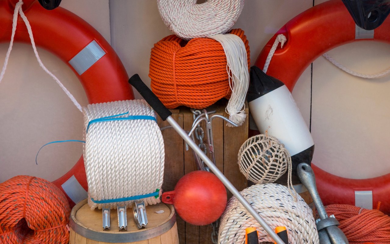 Red life rings and coils of orange and white rope among boating gear.