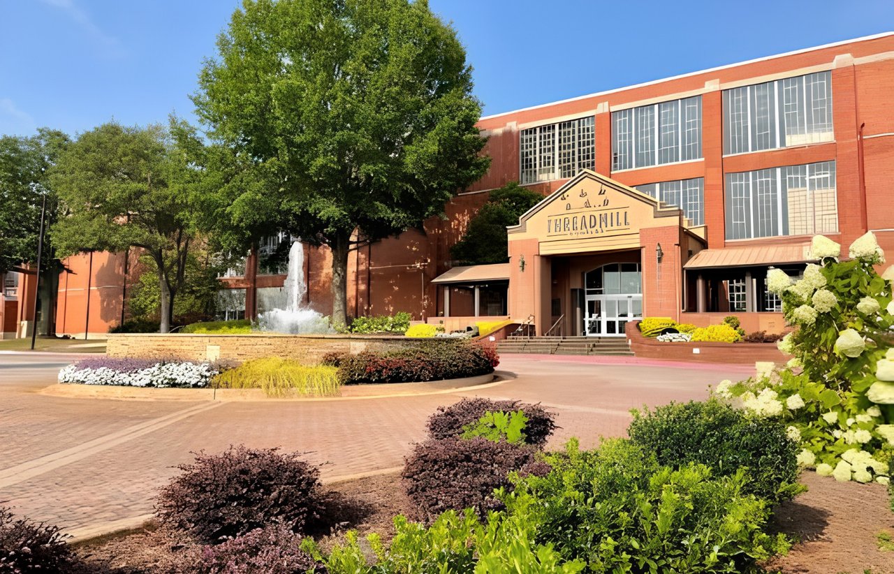 Red-brick commercial building with a fountain and landscaped plaza.