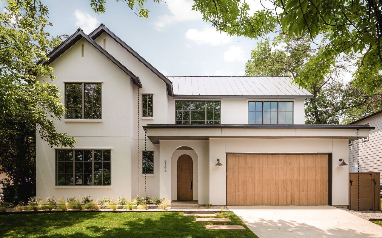 Modern two-story white house with an arched wood entry and wide wooden garage door.