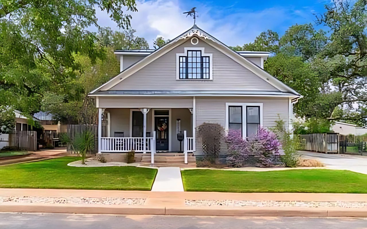  A picturesque two-story house with light grey siding and a dark grey roof.