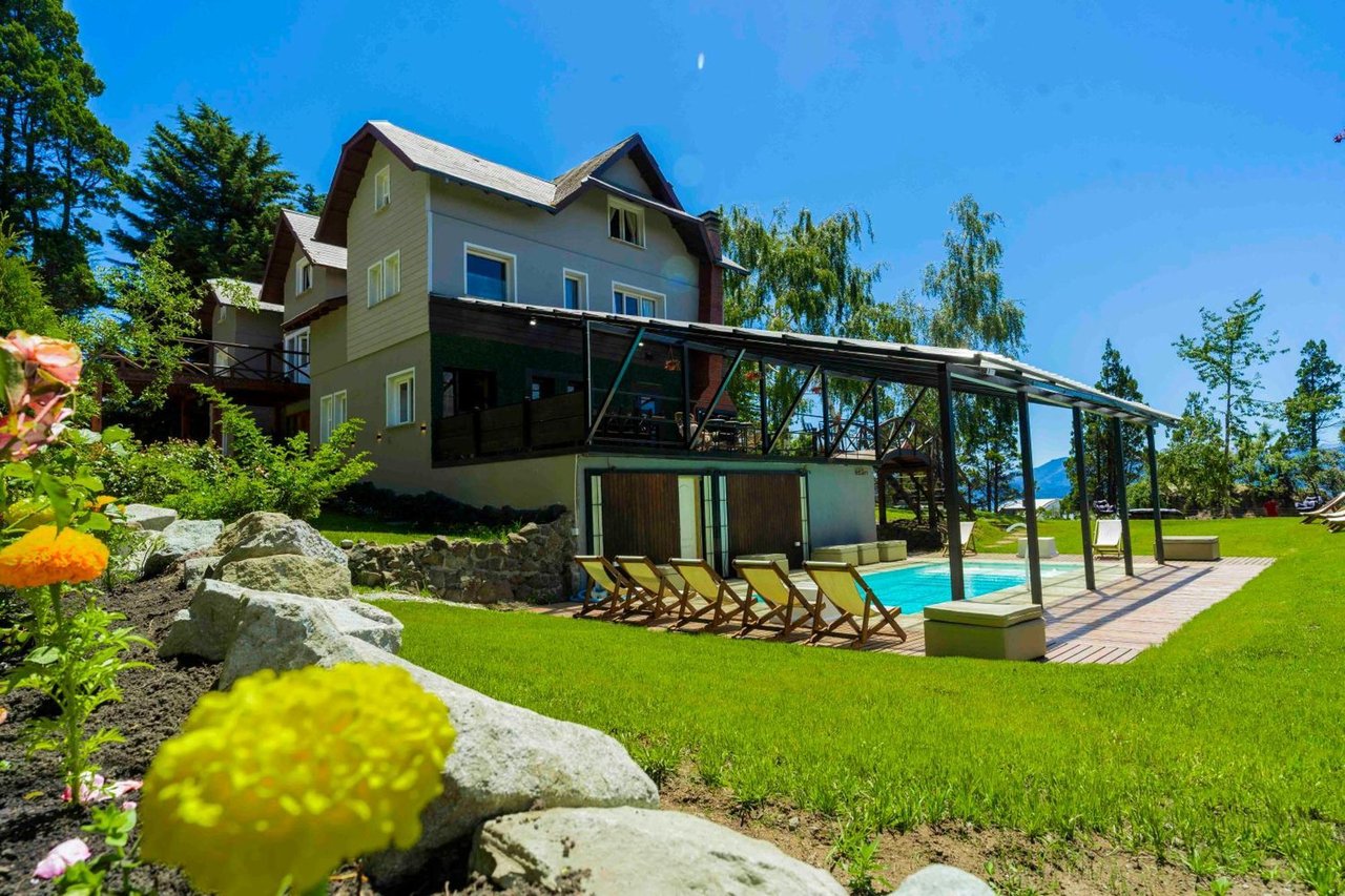 Boutique hotel exterior with a covered pool patio, lounge chairs, and landscaped gardens.