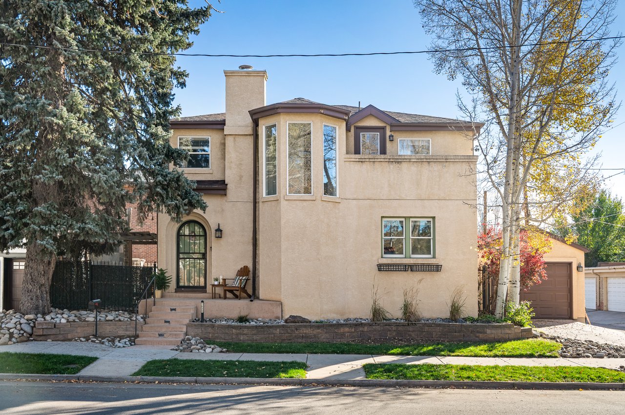 Two-story beige stucco house with a bay window, arched entry, and attached garage.