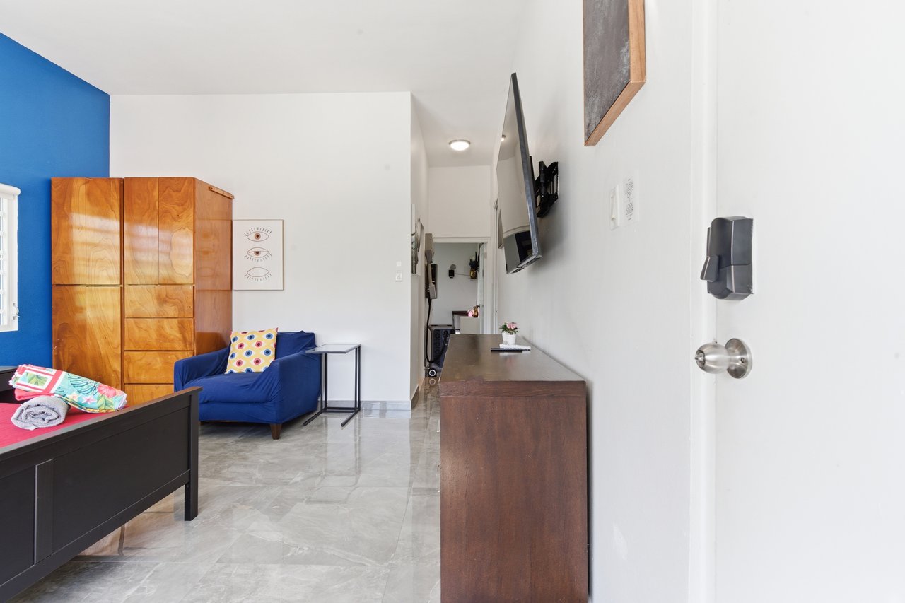 Living room with a blue accent wall, blue sofa, wood cabinets, and wall-mounted television.