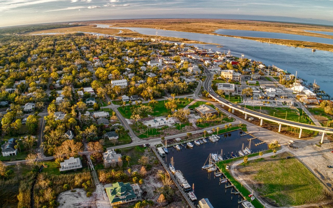 Aerial view of Puerto Los Cabos marina, with boats, waterfront buildings, and a bridge.
