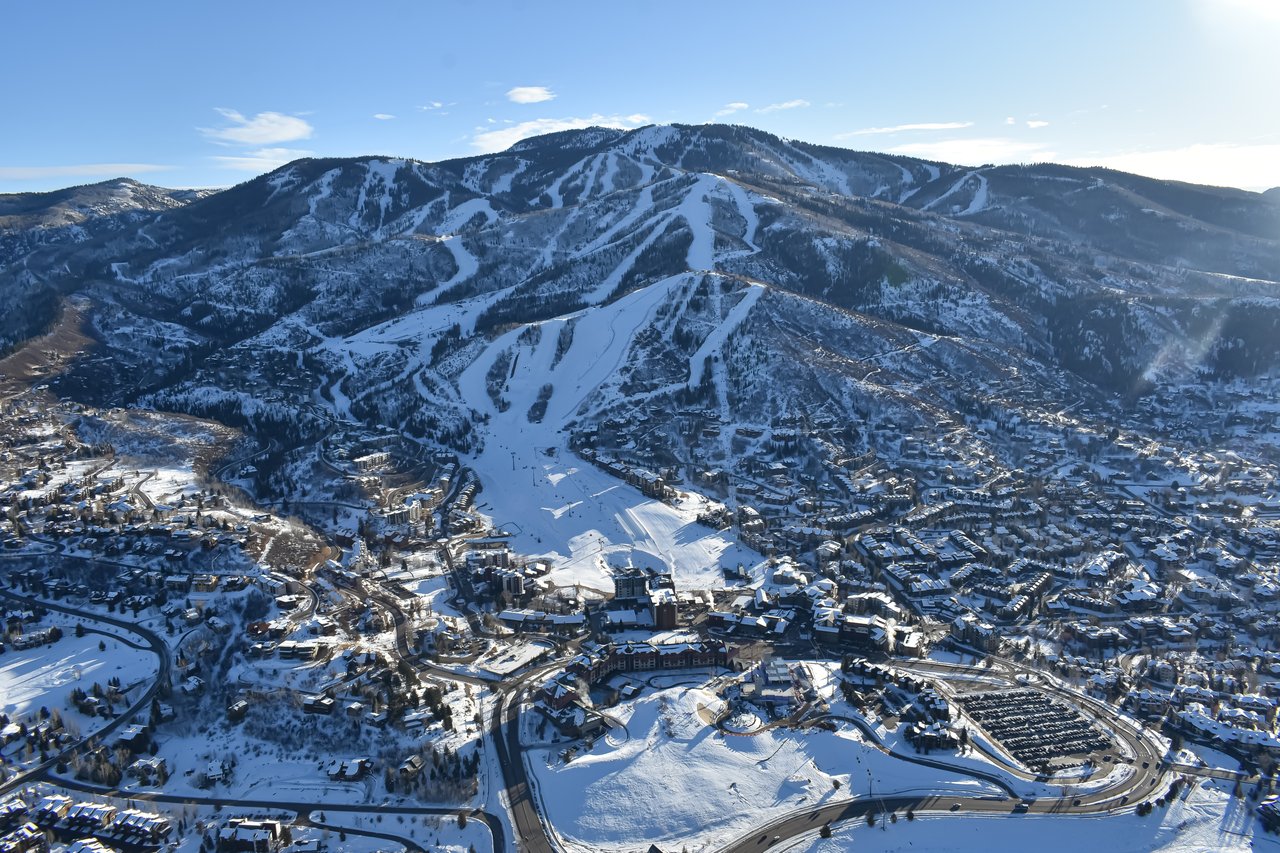 Snow-covered ski resort town beneath groomed mountain runs.