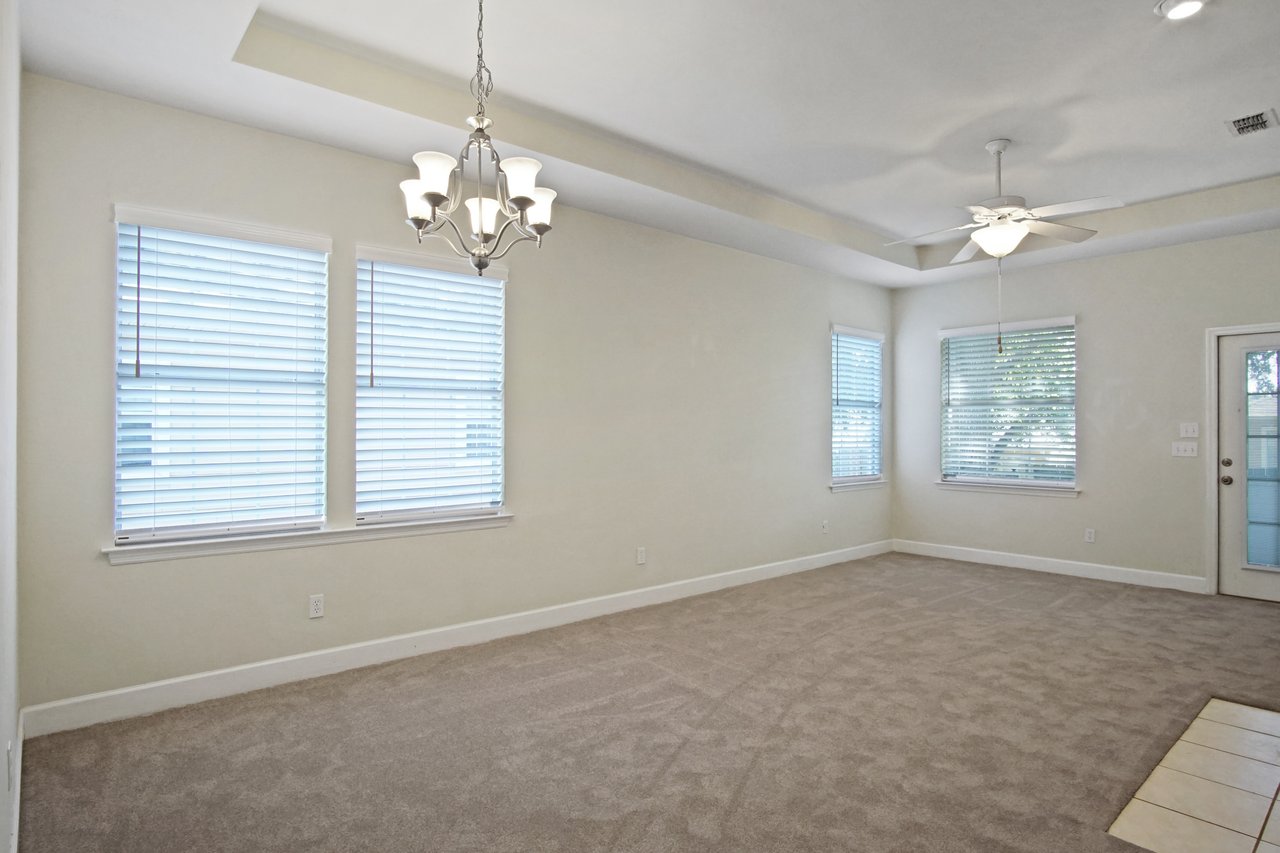 Living and dining area at 5441 Hampton Hill Circle, Tallahassee, Florida 32311 with tray ceiling, chandelier, ceiling fan, and carpet flooring.