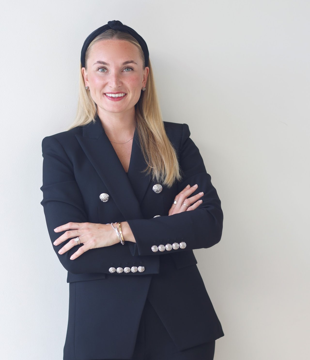 Hana Prawdzik smiling with her arms crossed in a navy blazer.