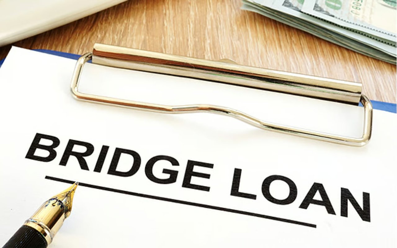 Bridge loan document on a clipboard beside a fountain pen and U.S. currency.