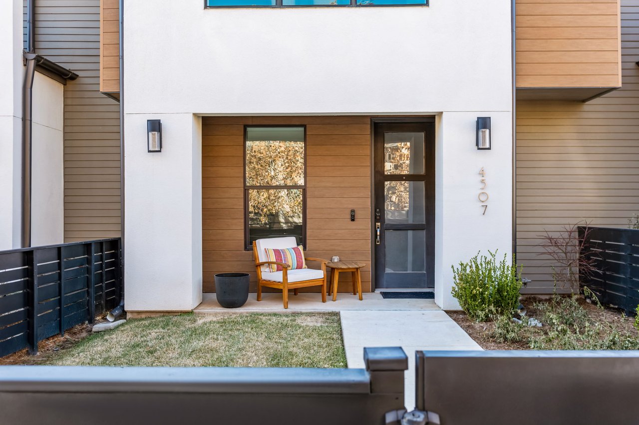 Covered front entry at 4507 Unity Circle in The Grove, Austin, with wood and stucco elevation details and a black board and batten door, built by M Signature.