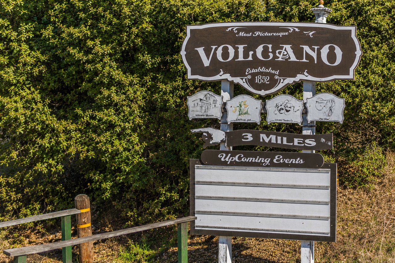 Volcano town sign noting its 1852 establishment, with attraction signs and an events board.