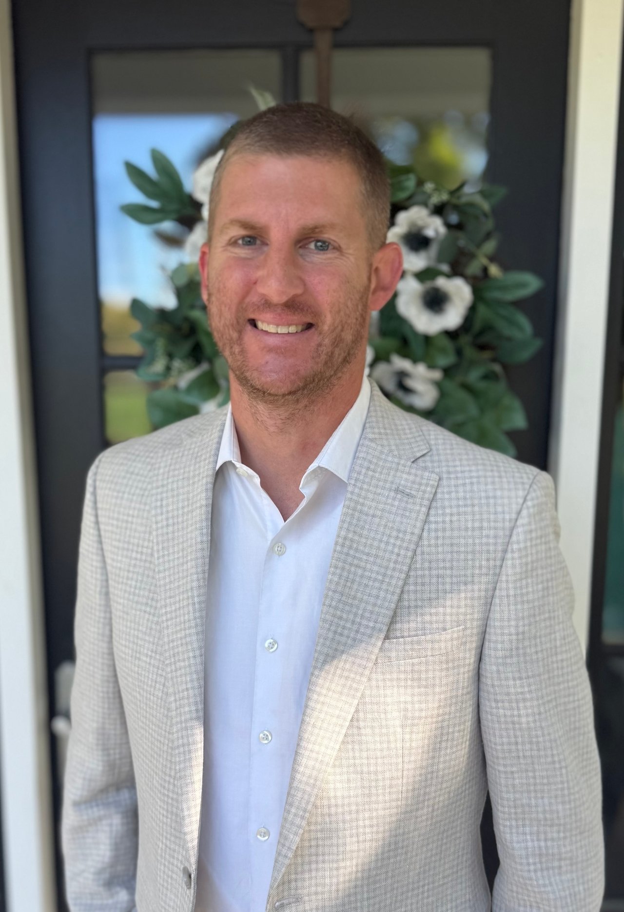Brent Kennedy smiling in a light checked blazer and white shirt.