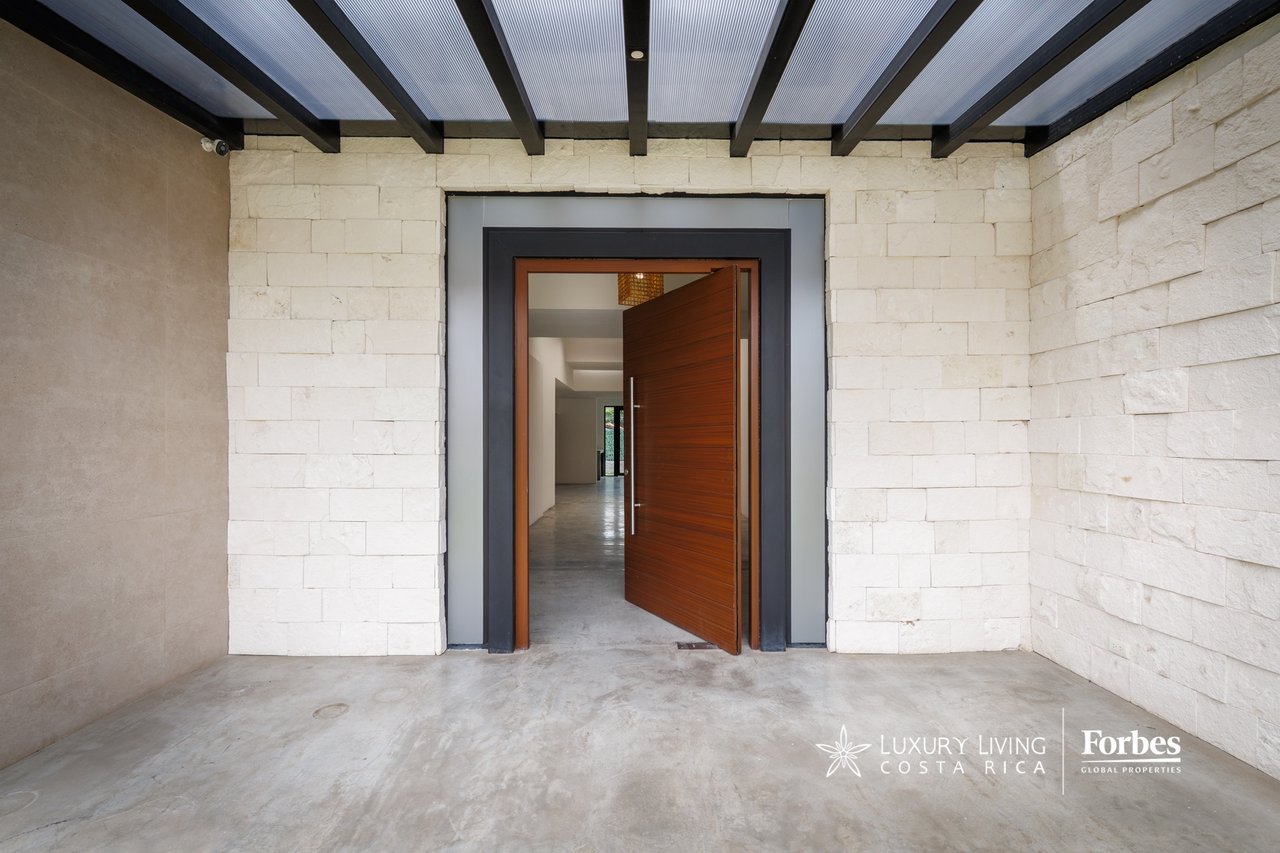 Modern home entrance with pale stone walls, an open wood door, and a translucent roof.