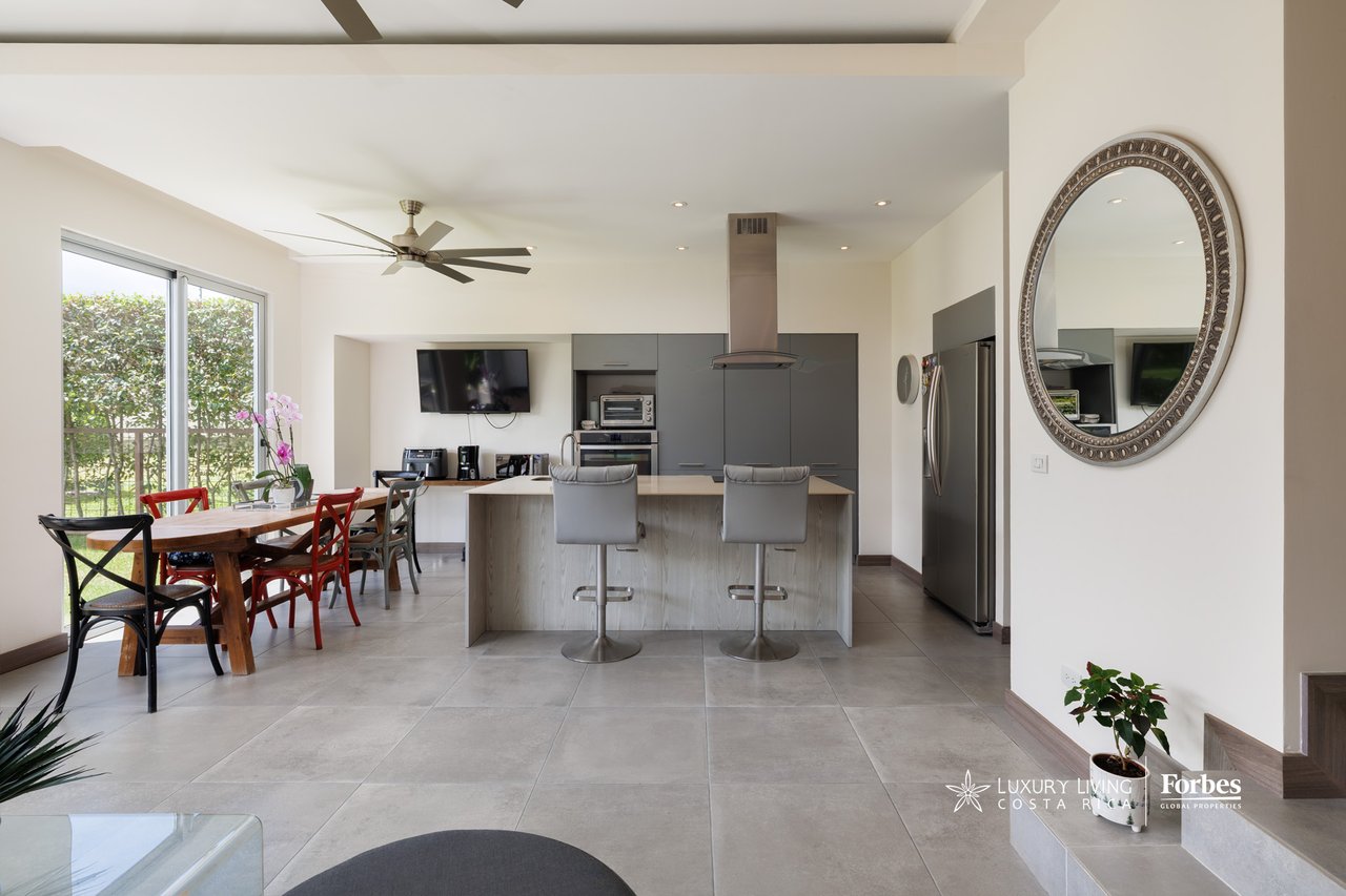 Open-plan kitchen and dining area with gray cabinets, a large island, and sliding glass doors.