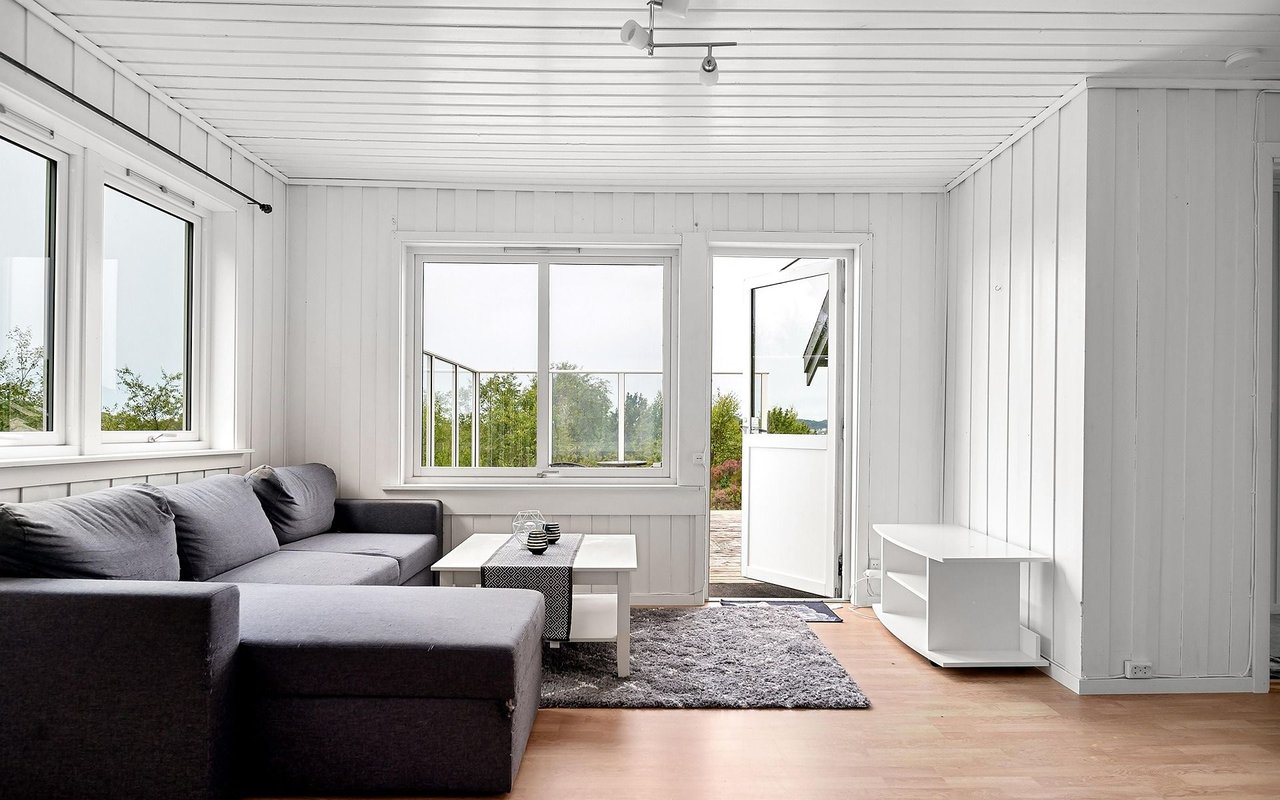 Bright living room with a gray sectional, white coffee table, and open door to the patio.