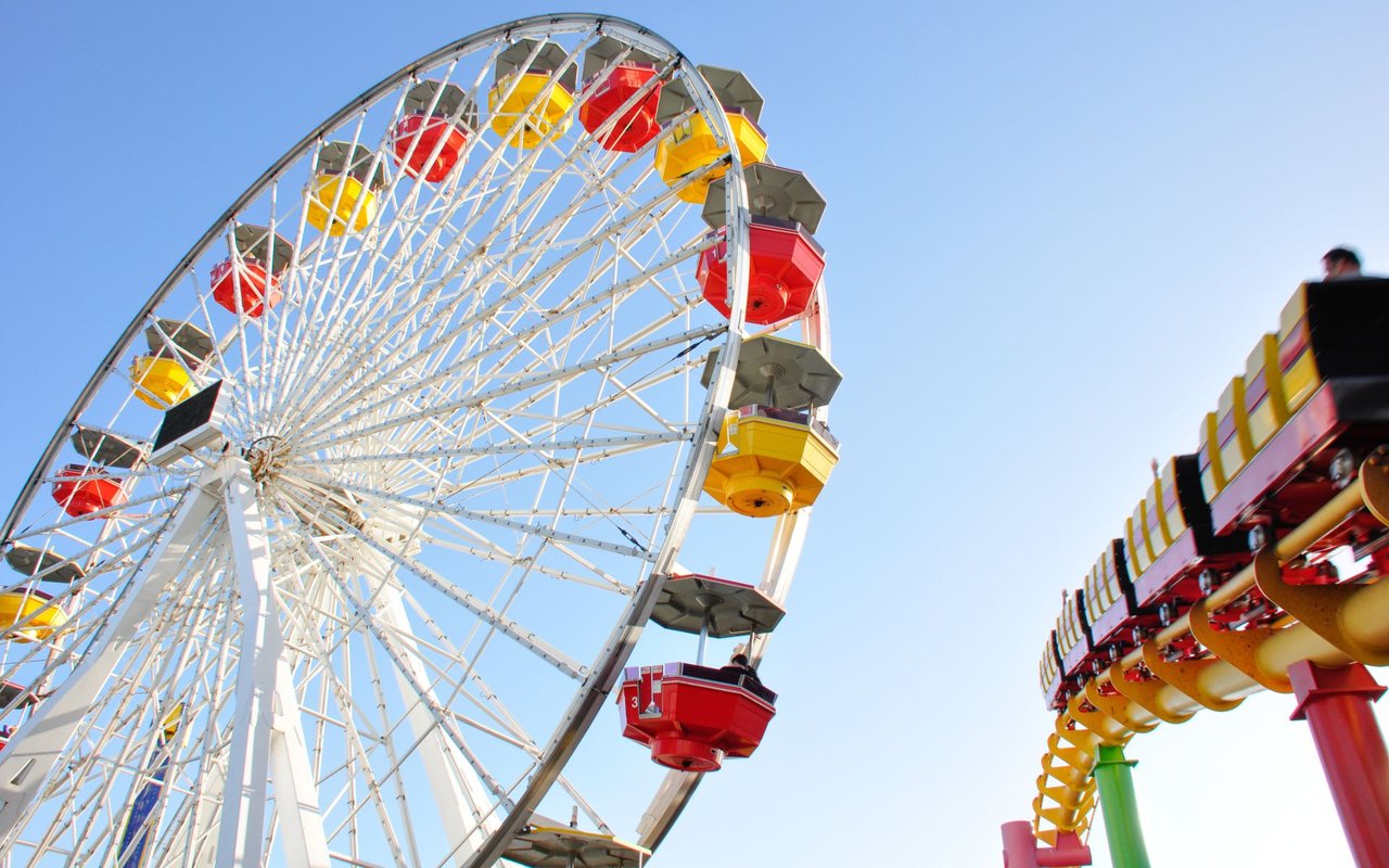 colorful teacup ferris wheel with a roller coaster on the right