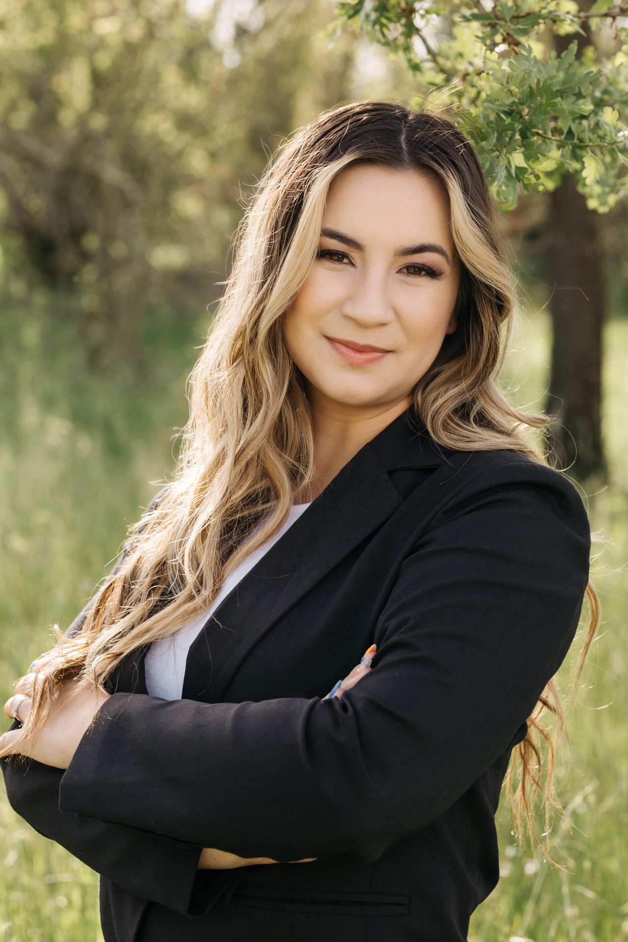 Haylee Lynn-Tate in a black blazer, standing outdoors with her arms crossed.