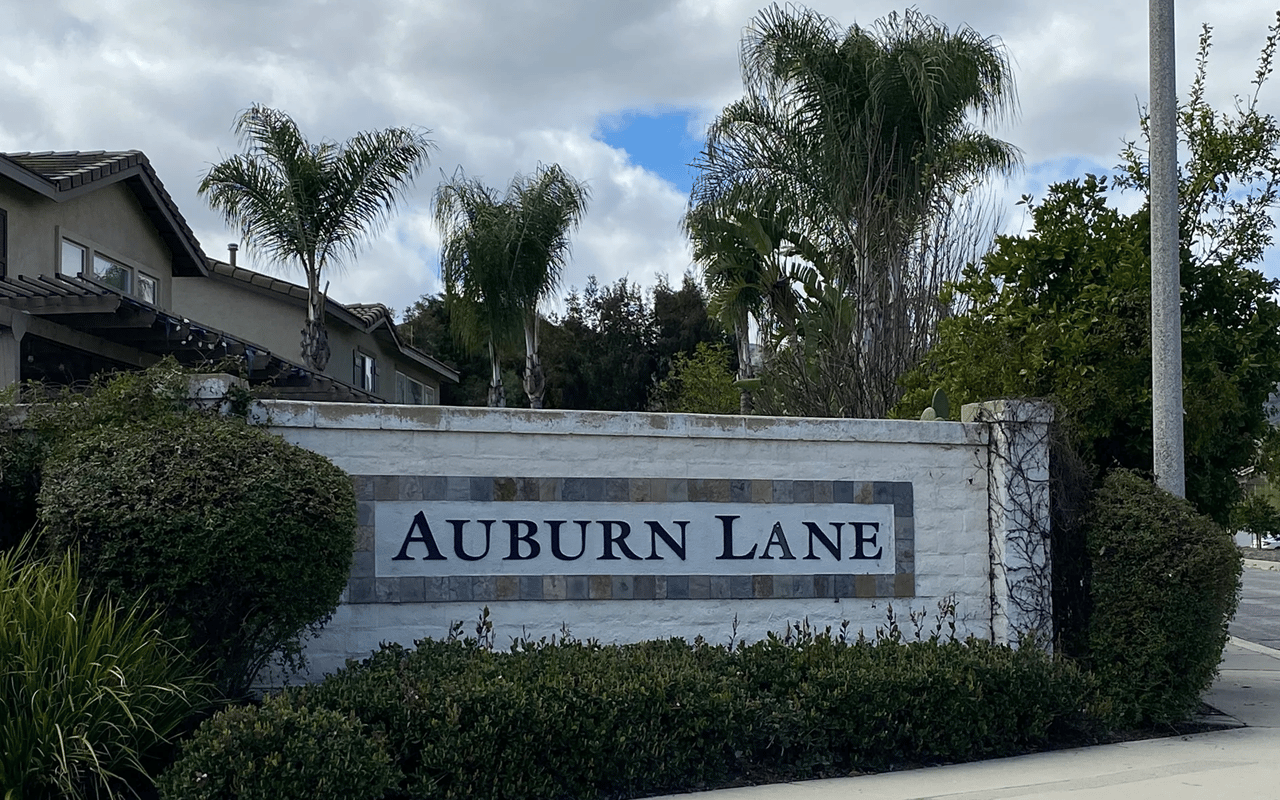 Stone monument sign marking the entrance to the Auburn Lane community in Lake Elsinore, California.