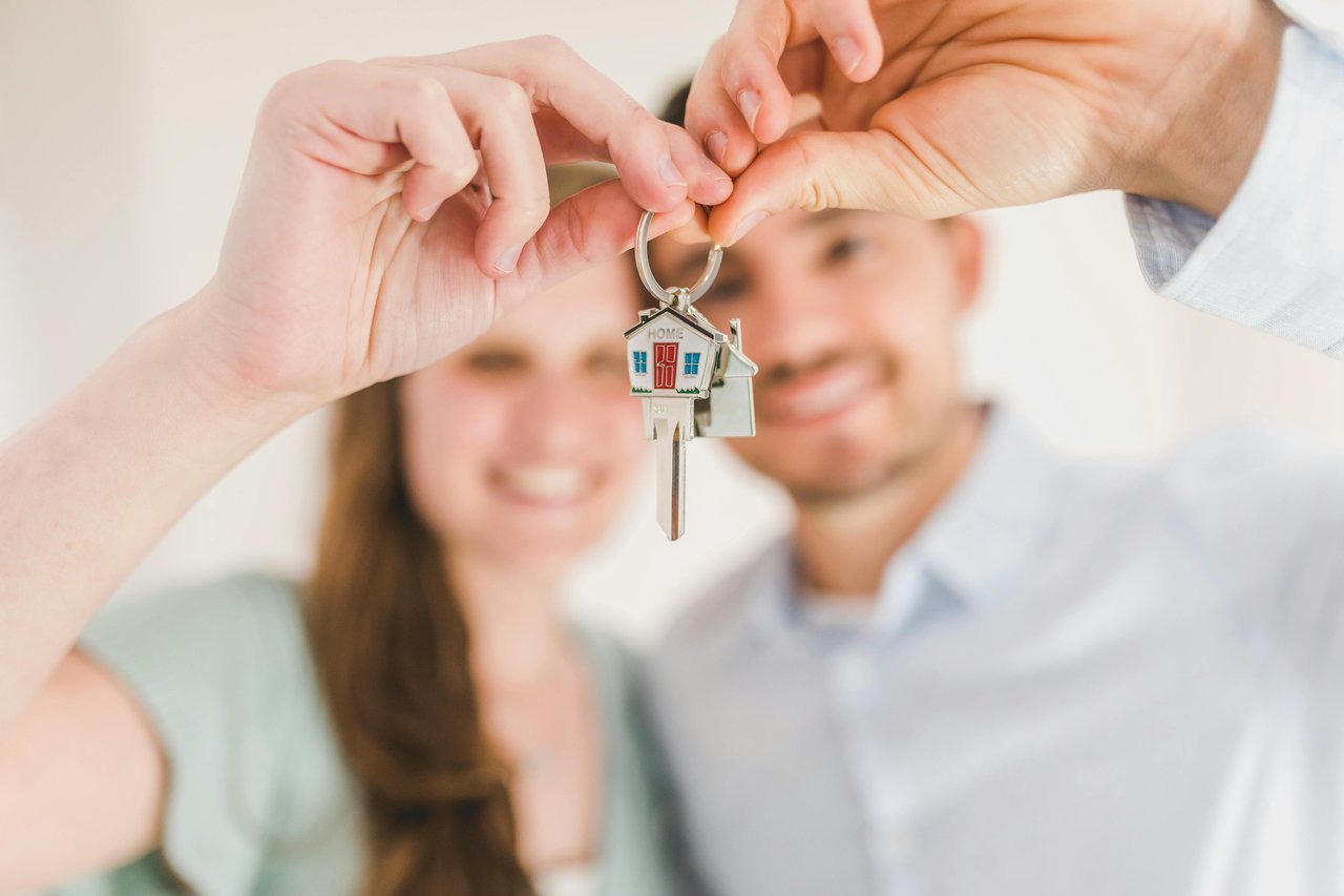 A couple receives a key attached to a small house-shaped keychain.