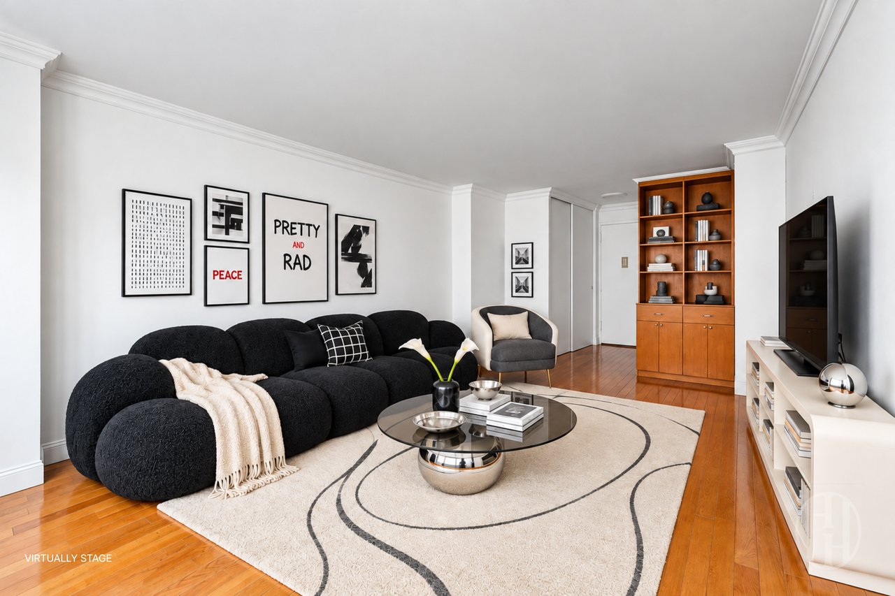 Living room with a black sectional, cream patterned rug, wood floors, and built-in shelving.