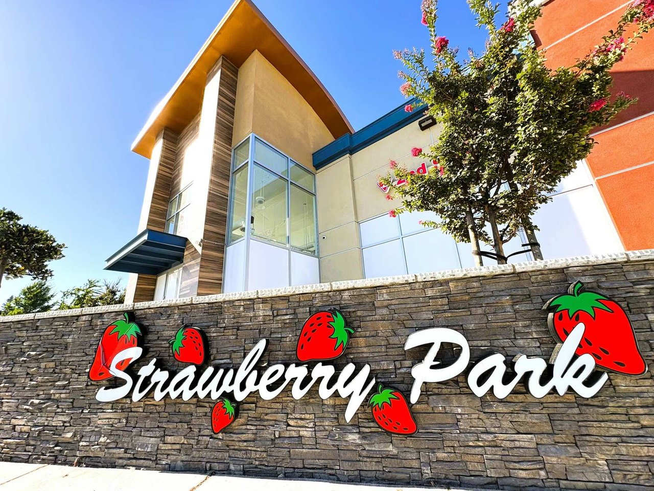 Strawberry Park shopping center entrance, marked by a large sign on a stone wall.