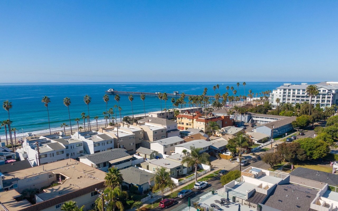 Aerial view of Oceanside’s shoreline, pier, palm-lined streets, and coastal homes.