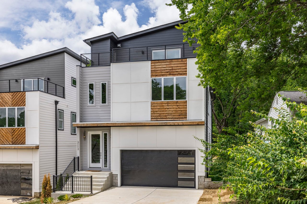 A modern house with a black garage door and a driveway.