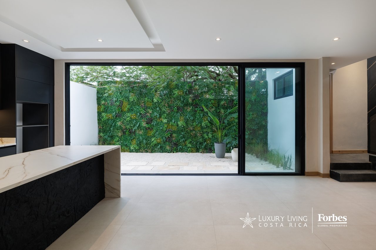 Modern kitchen with a marble island and glass doors overlooking a lush private patio.