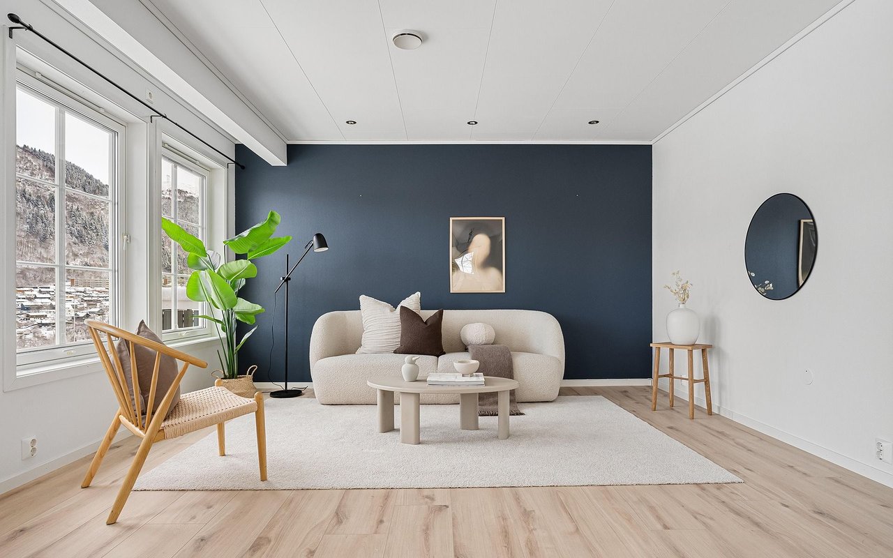 Living room with a cream sofa, dark blue accent wall, and large windows overlooking mountains.