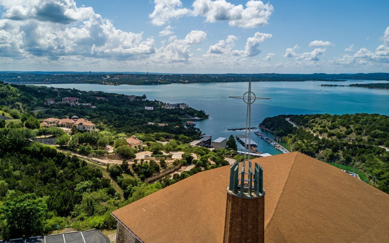 Aerial view of a lakeside neighborhood, marina, and terracotta-roofed building.