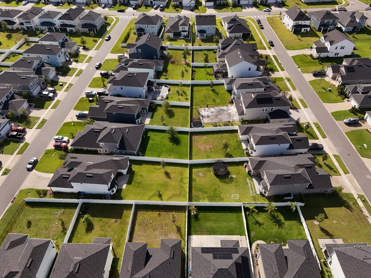 Aerial view of detached homes with fenced yards along two neighborhood streets.