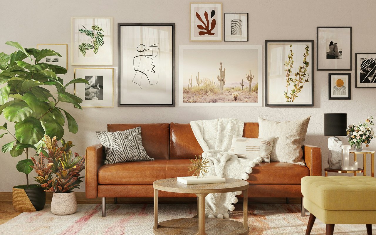 Furnished living room with a caramel leather sofa, gallery wall, and leafy plants.