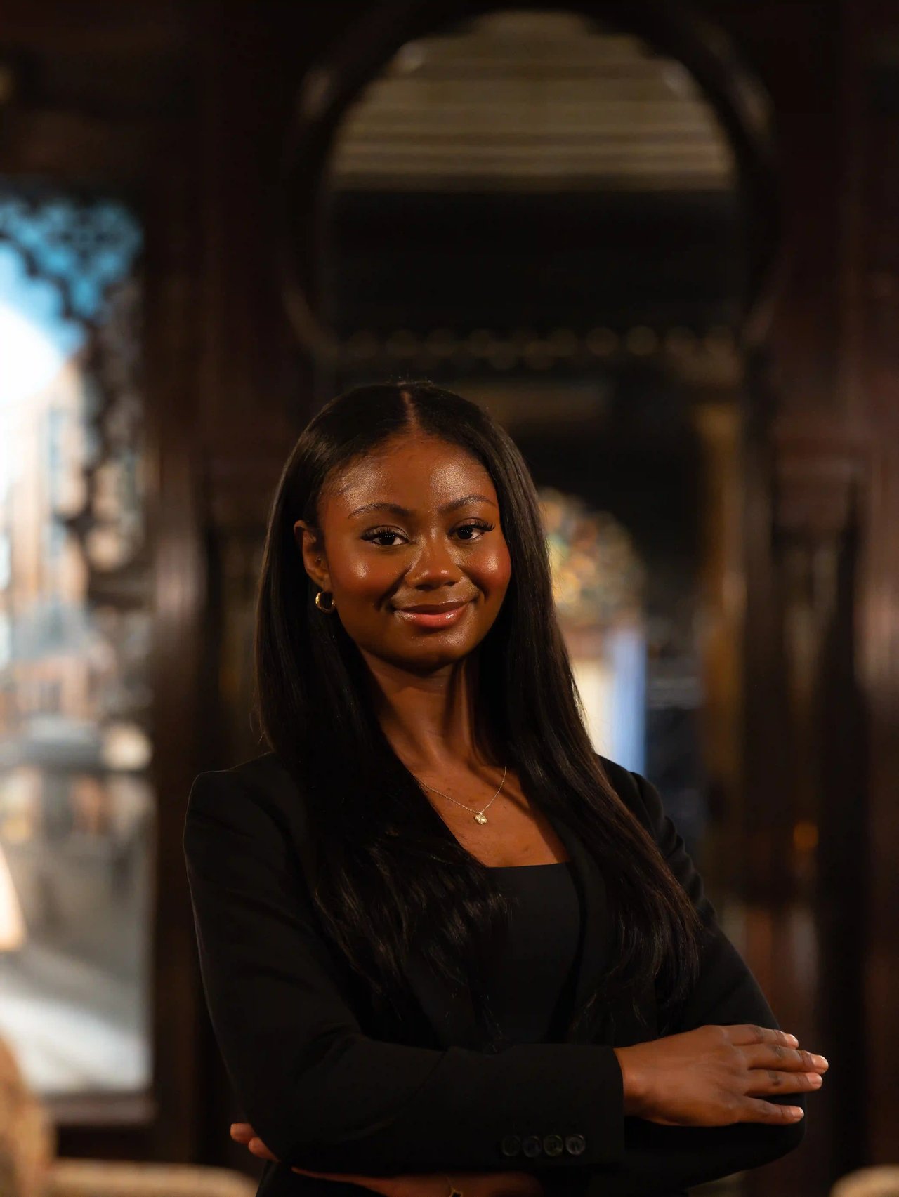 Amya Henley, Milwaukee realtor with the Luxe Haven Group, smiling with arms crossed inside an elegant interior.