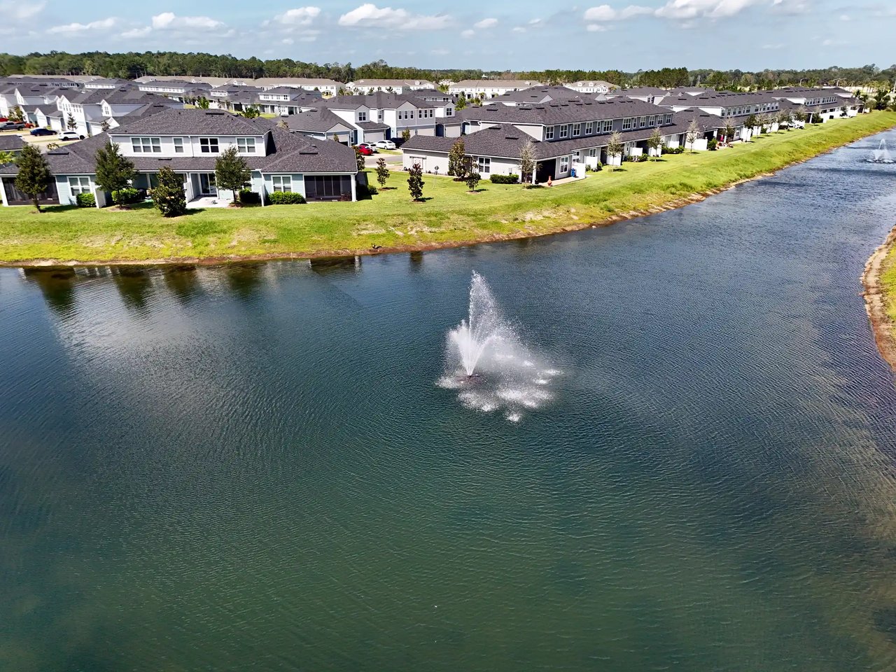 Aerial view of homes along a pond with a fountain in Cherry Elm at Silverleaf.