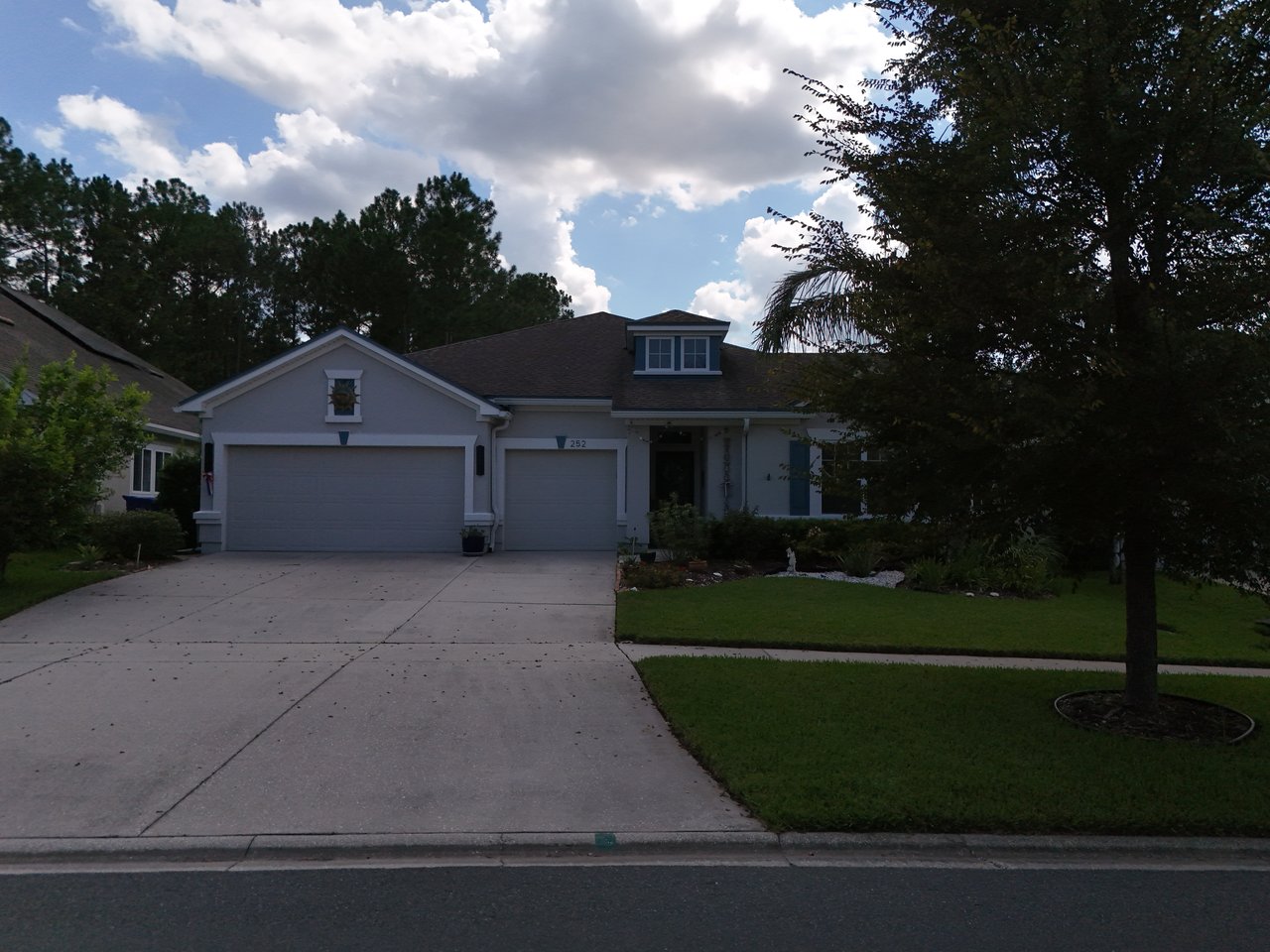 Single-story home with a two-car garage, wide driveway, and mature trees in Greenleaf Village.
