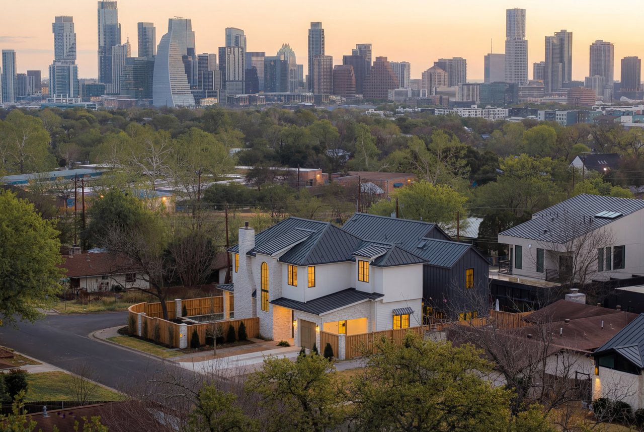 Modern Austin home with a dark metal roof and downtown skyline behind it.