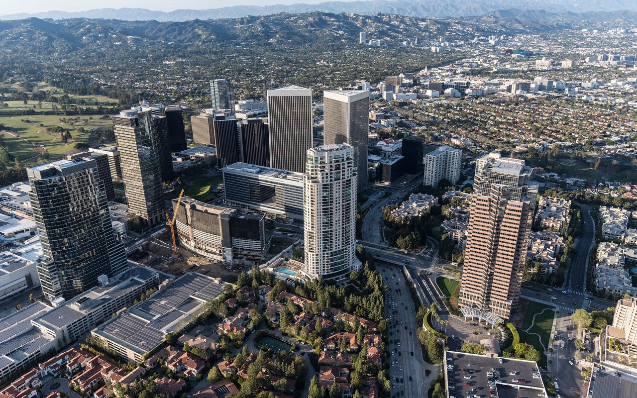 Aerial view of Century City’s high-rise towers, surrounding neighborhoods, and distant mountains.