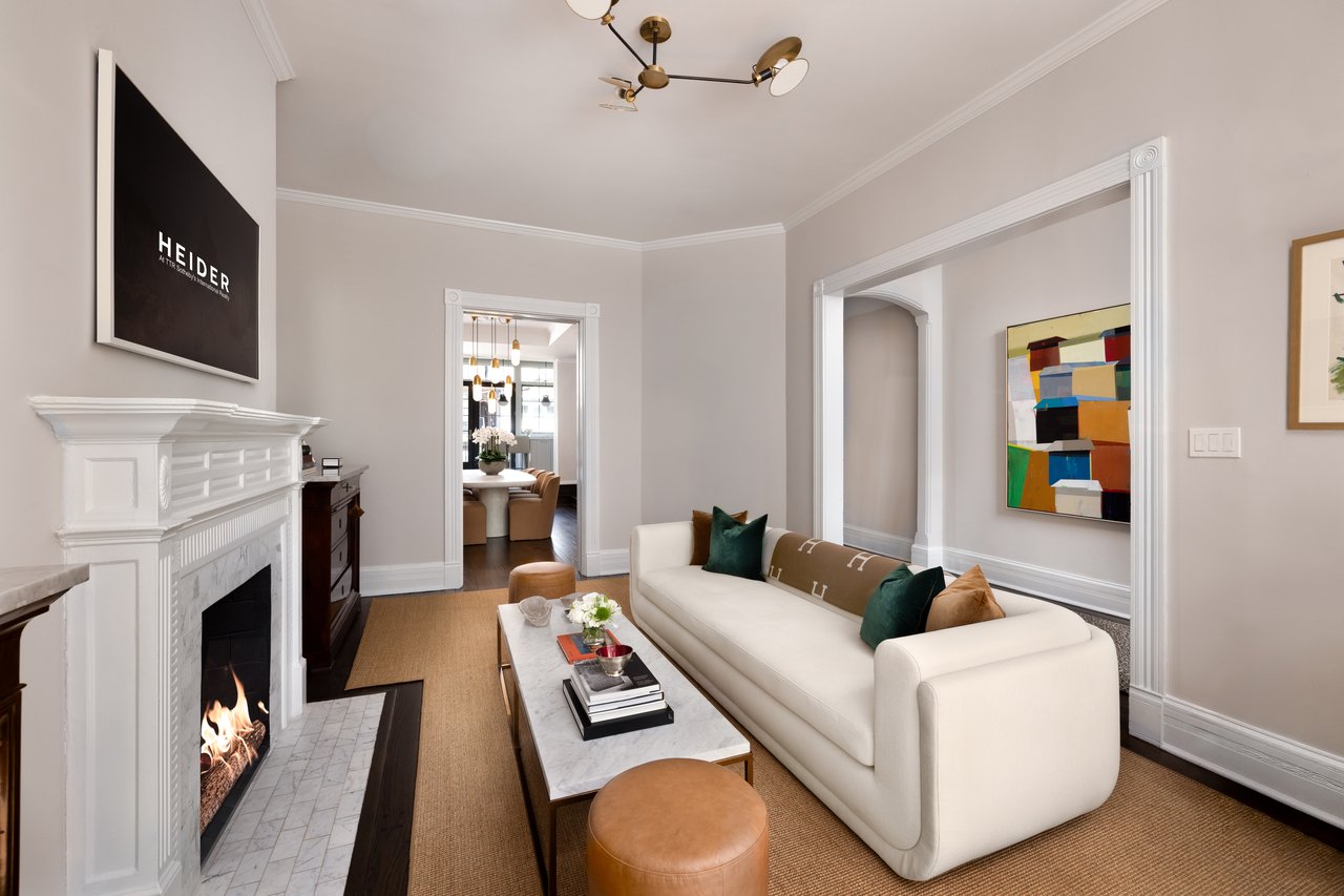 Living room with a white sofa, marble fireplace, and colorful abstract wall art.