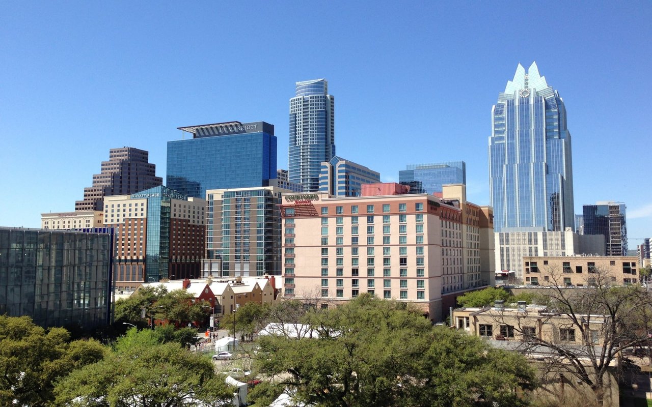 Downtown Austin skyline with the JW Marriott and Hyatt Place towers above tree-lined streets.