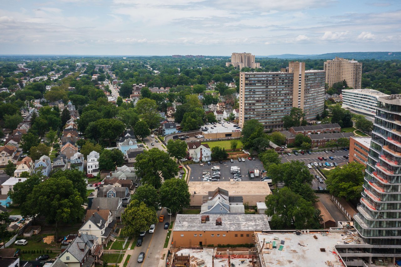 An aerial view of a residential area with houses, driveways, yards, and trees lining the streets.