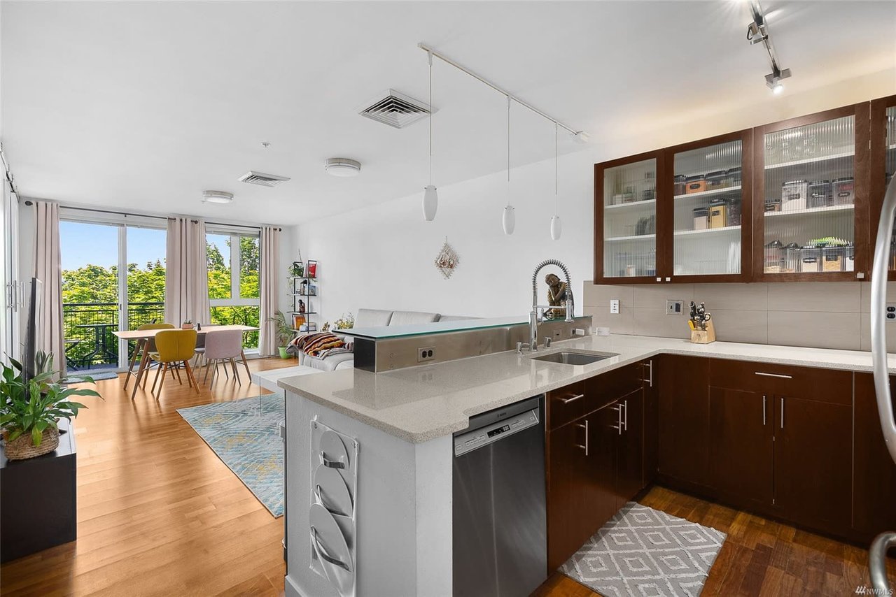 Airy and modern kitchen with dining space leading to a sunny balcony in a luxury urban condo.