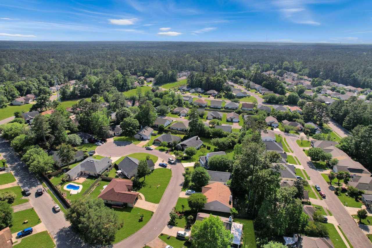 An aerial view of the Killearn Lakes community, showing houses, streets, and surrounding greenery.