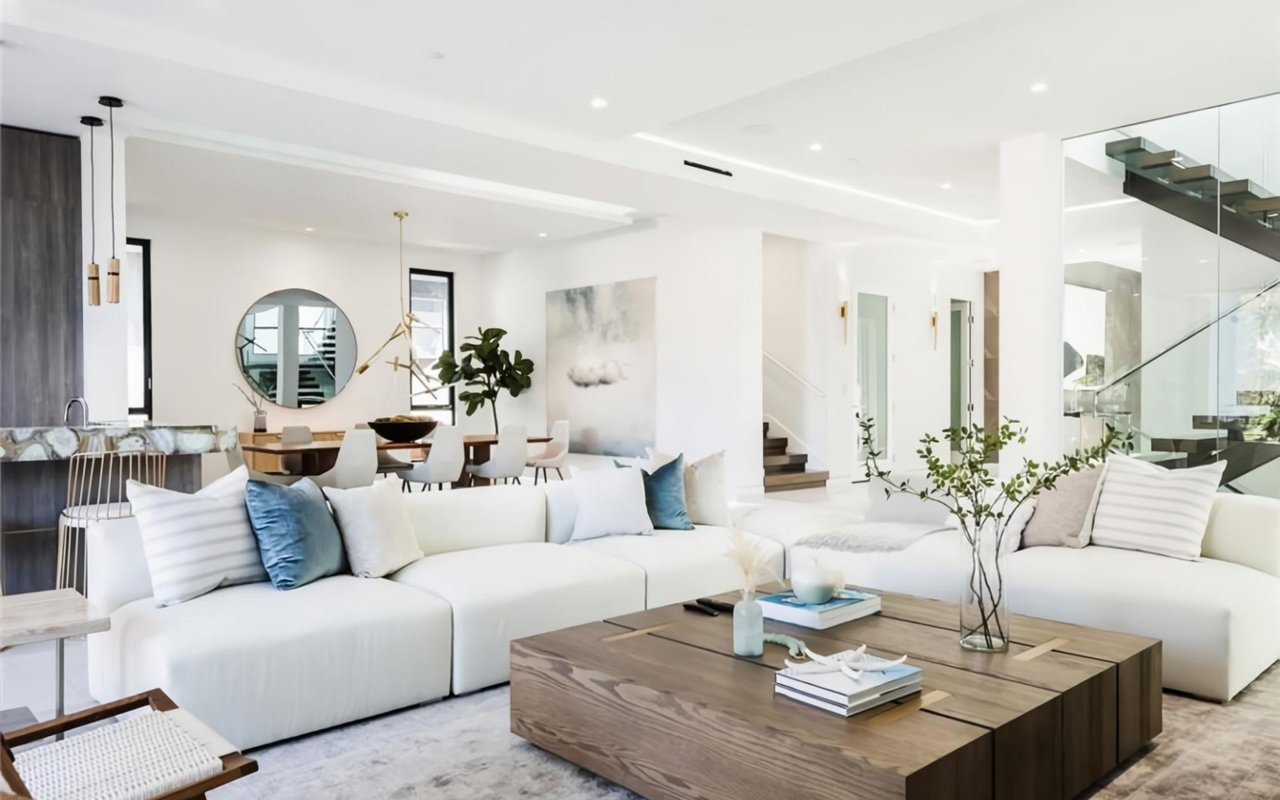 Spacious, modern living room with white sofas, a wooden coffee table, and minimalist decor.