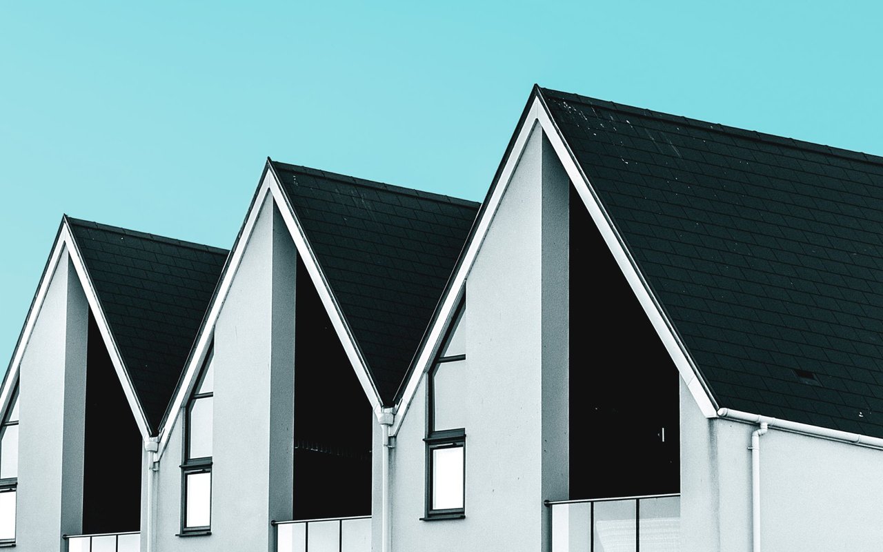 White homes with steep dark gabled roofs stand in a repeating row.
