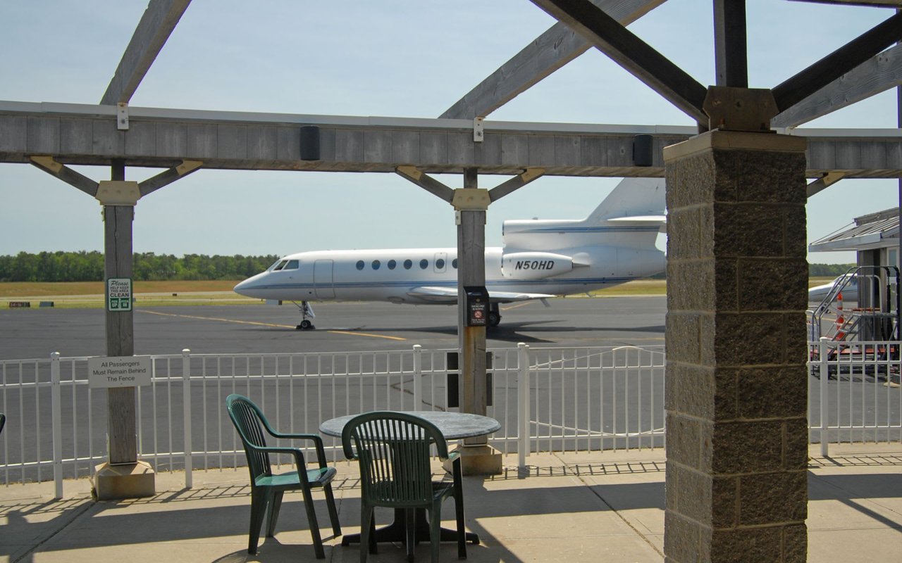 A white private aircraft parked on an airport runway.