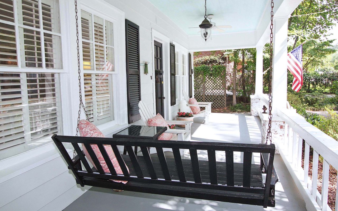 A wooden porch swing hanging from the ceiling of a porch