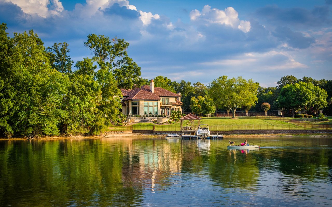 A kayak, canoe, and paddleboard lined up neatly on a wooden dock on a calm lake.